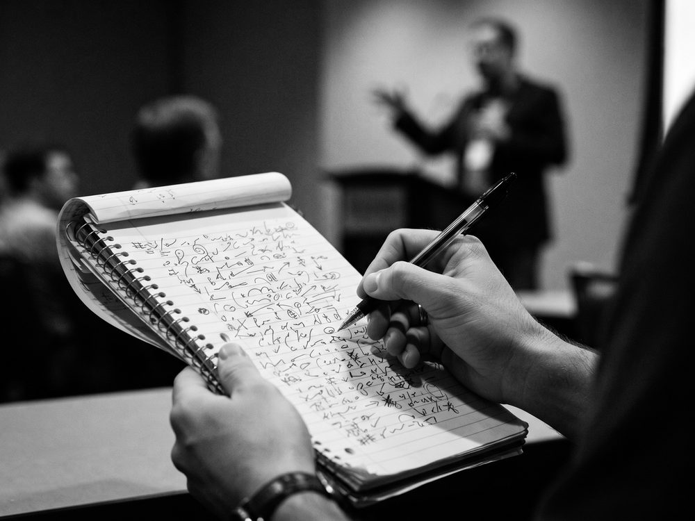 Notizblock mit Symbolen der Notizentechnik, eine Hand mit Stift